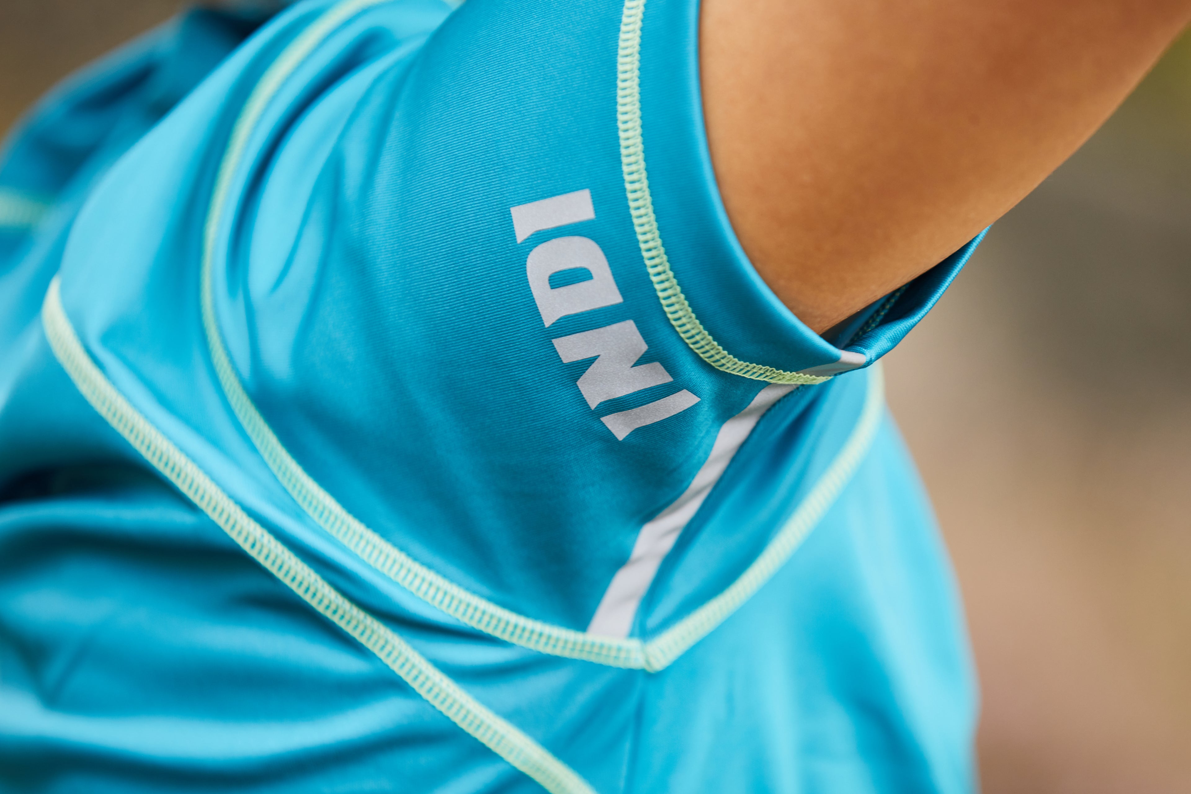 Close up of the arm of a blue running t-shirt with the INDI written logo visible